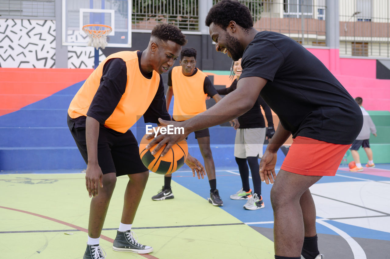 Black men playing basketball on sports ground