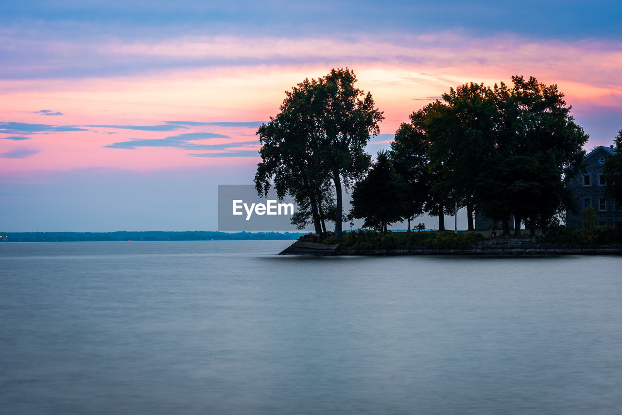 TREES BY SEA AGAINST SKY DURING SUNSET