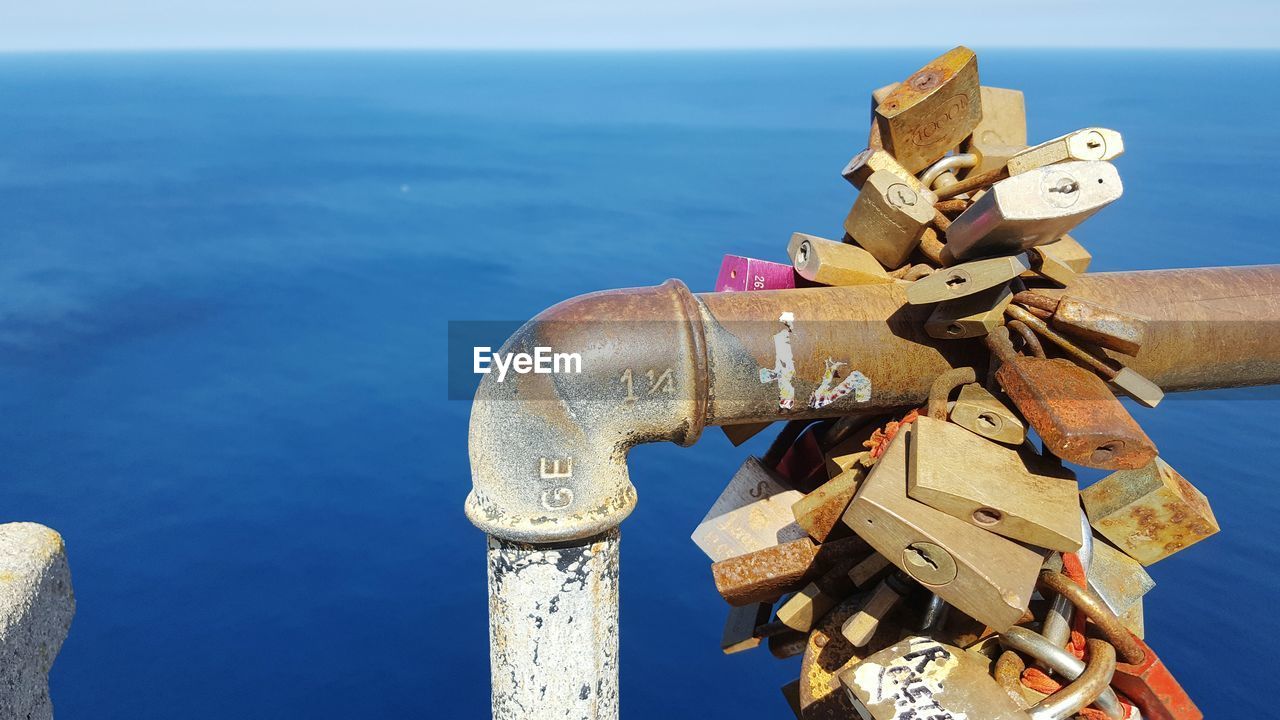 Rusty padlocks on pipe against sea