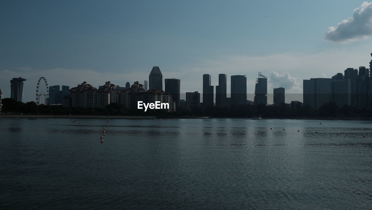 Sea by buildings against sky in city