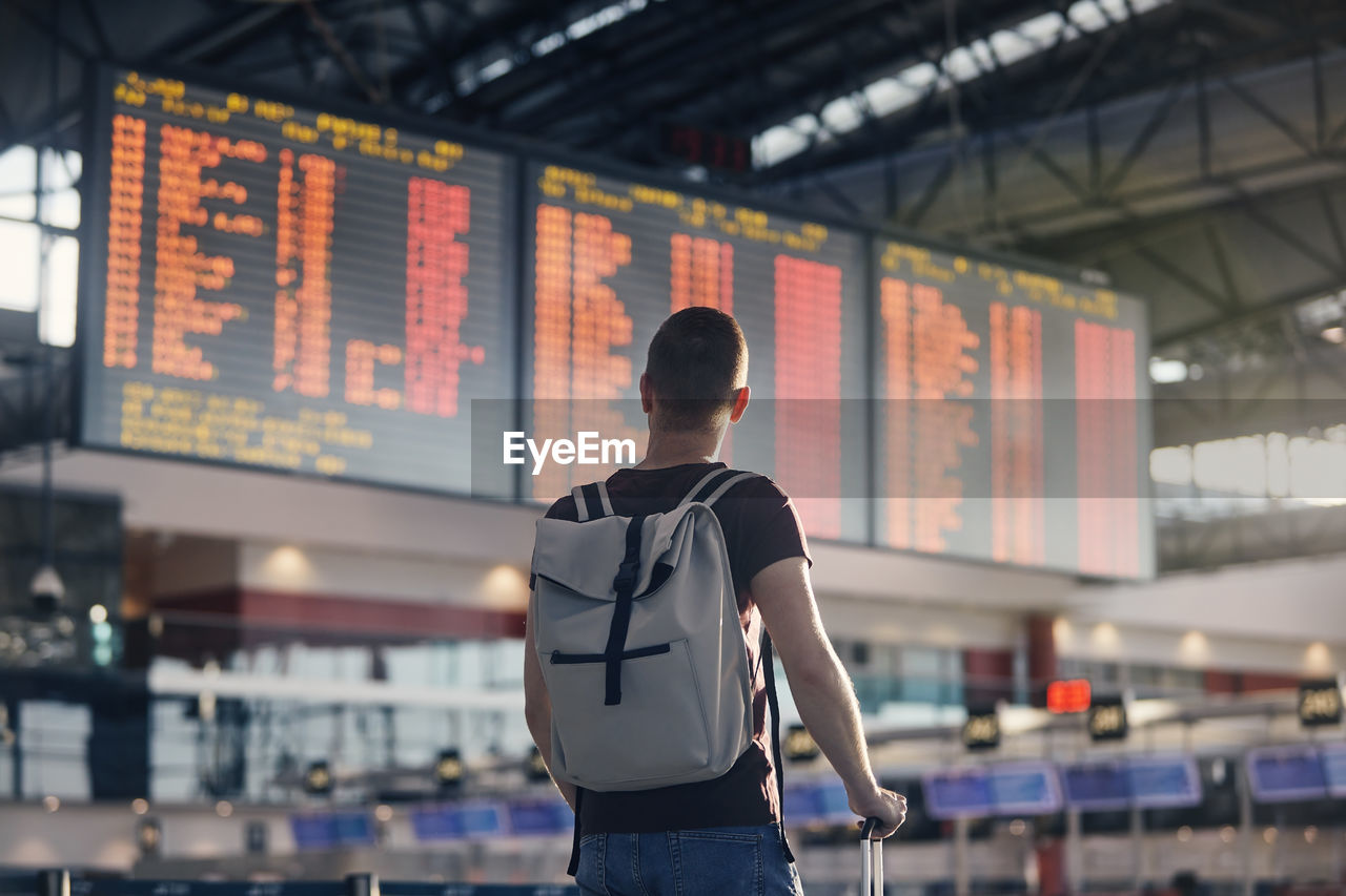 Traveling by airplane. man walking with backpack and suitcase walking through airport terminal.