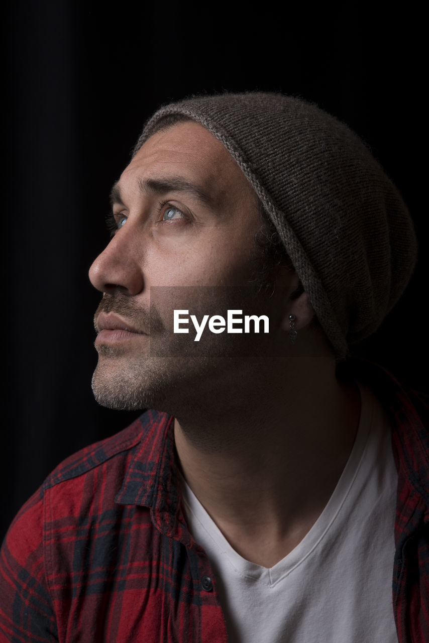 Close-up of man looking away against black background