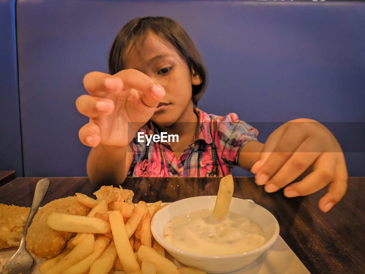 Close-up of girl having french fries in restaurant
