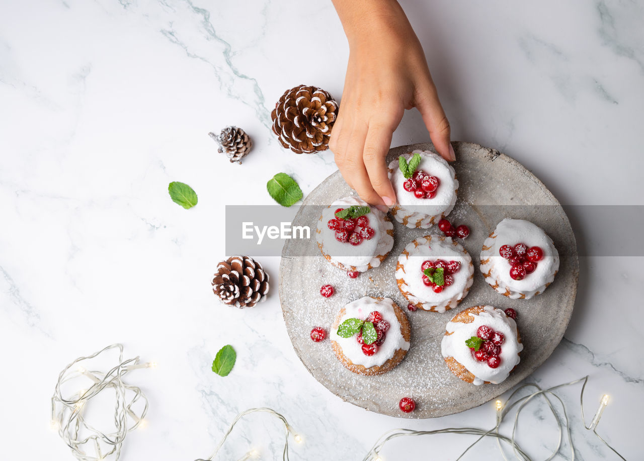 Cropped hand of woman holding christmas muffin on table