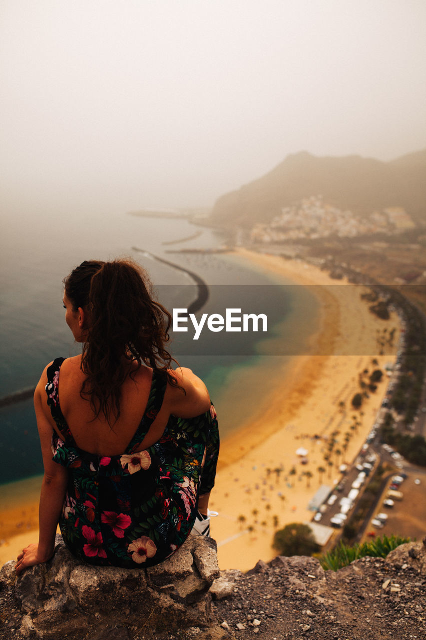 Rear view of woman looking at sea on cliff