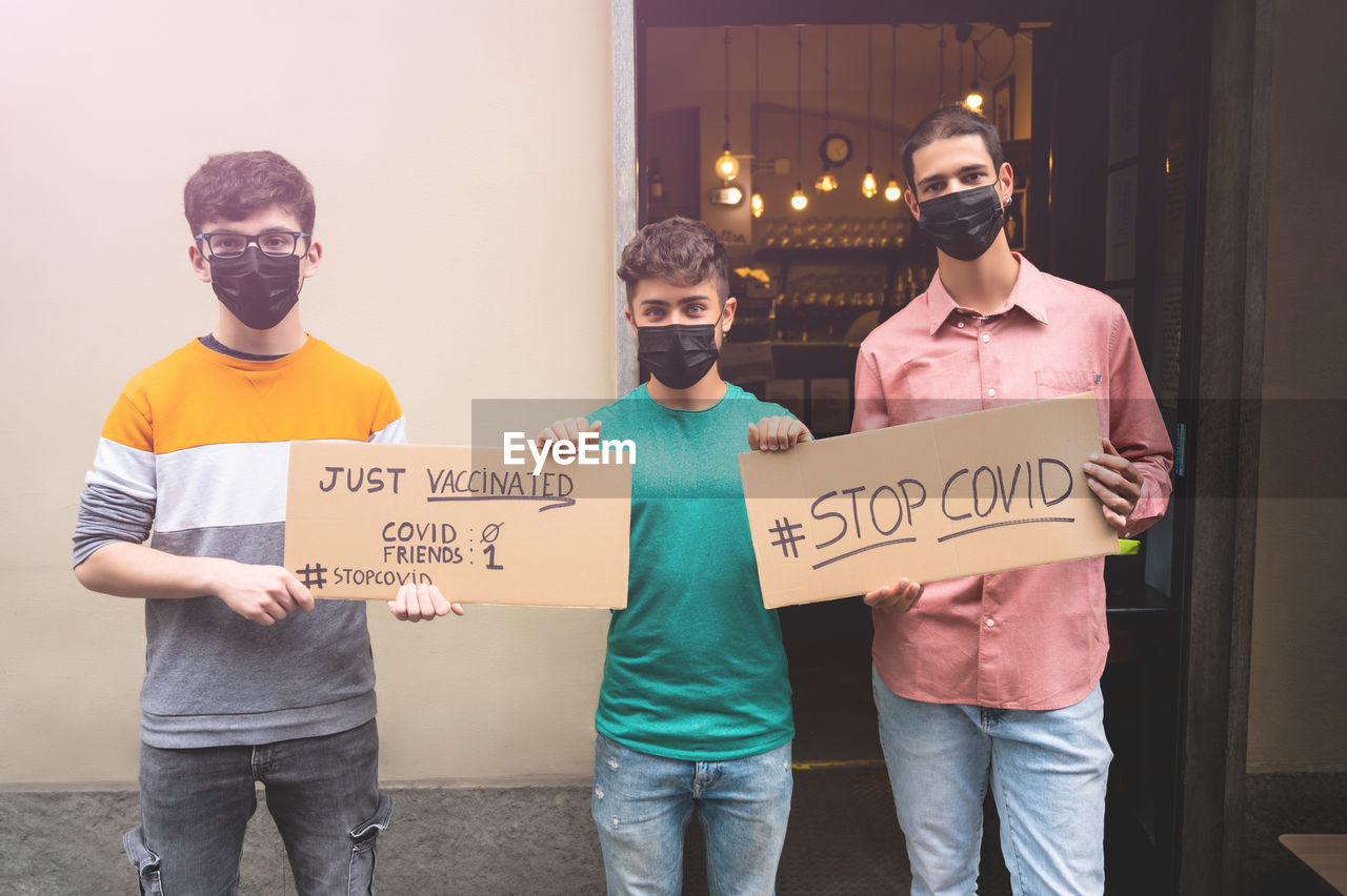 People wearing mask holding cardboard standing outdoors