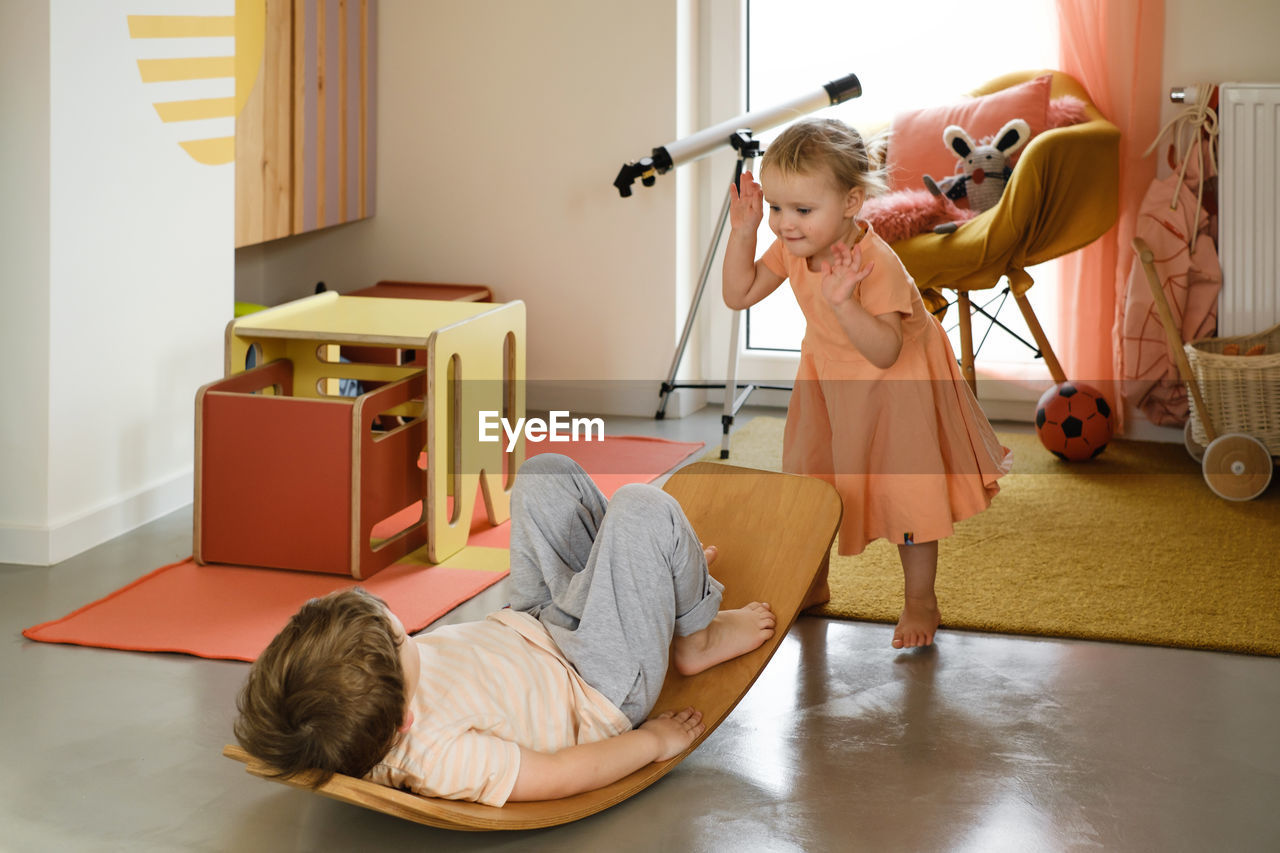 Child playing on balance board for toddlers in kids room. curvy rocker board used for motor physical