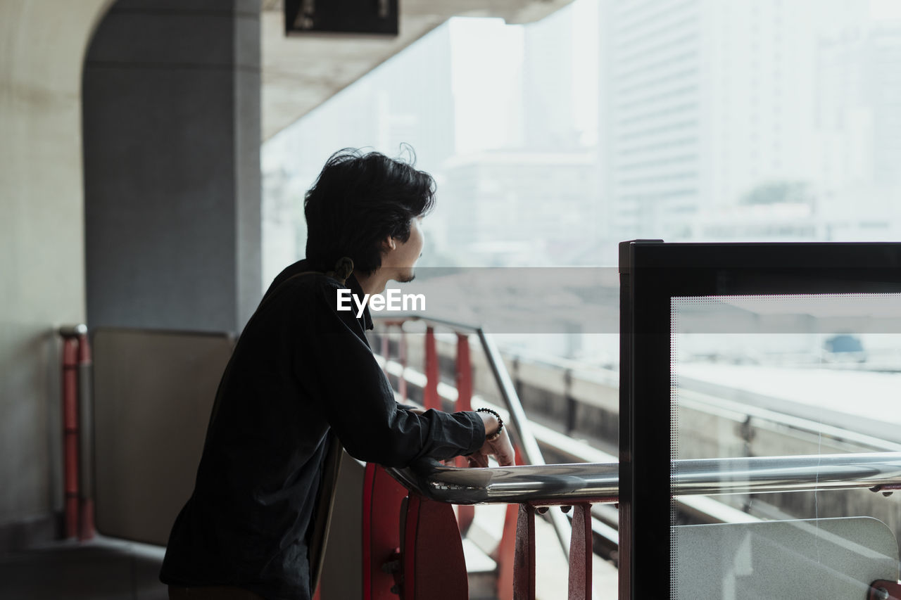 Side view of man standing by railing