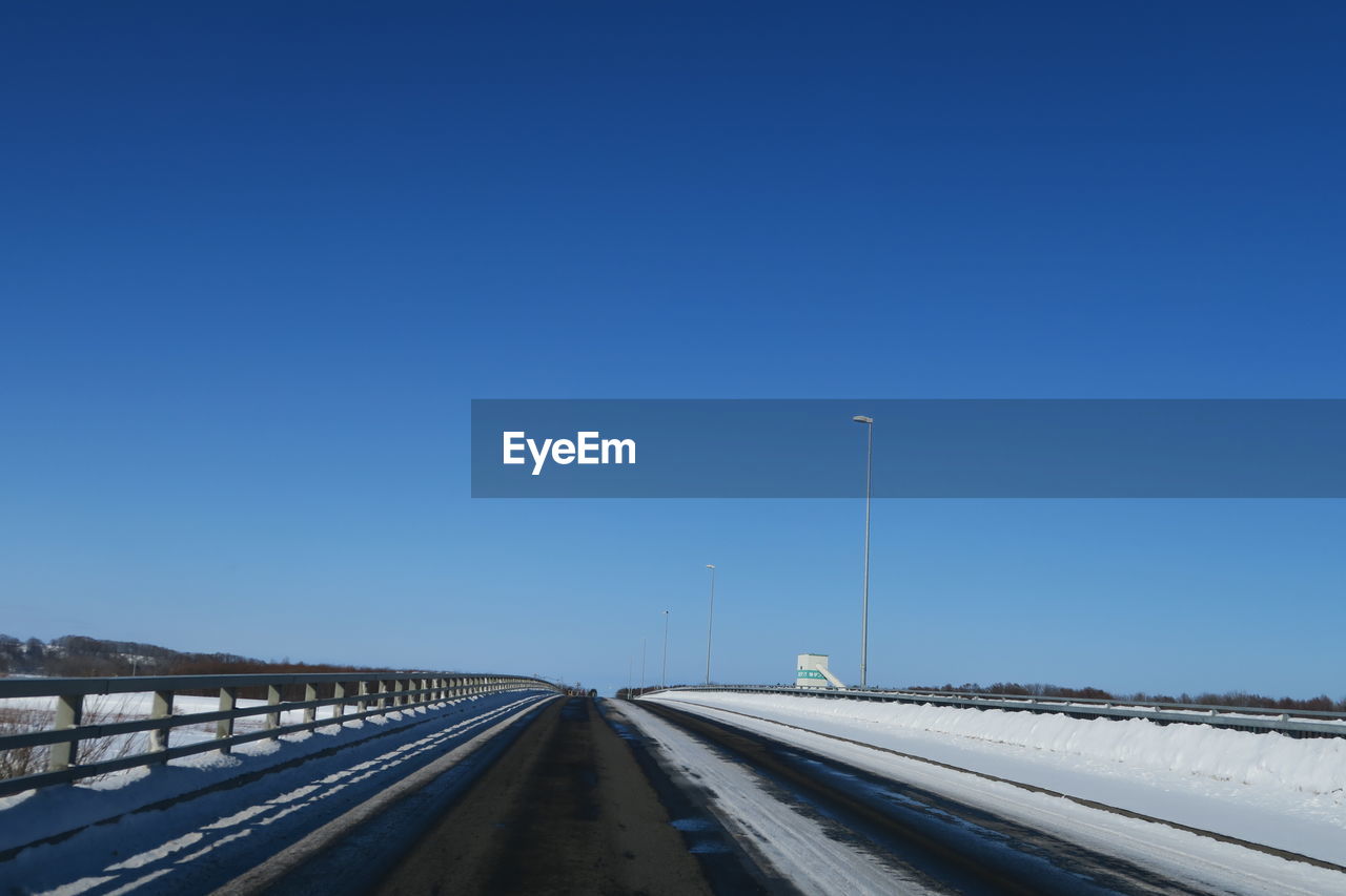 Road against clear blue sky during winter
