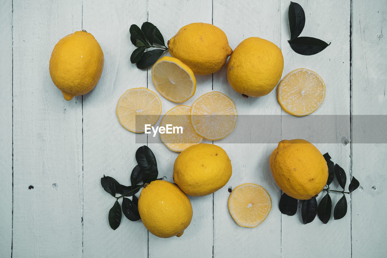 Lemons with leaves on wooden background