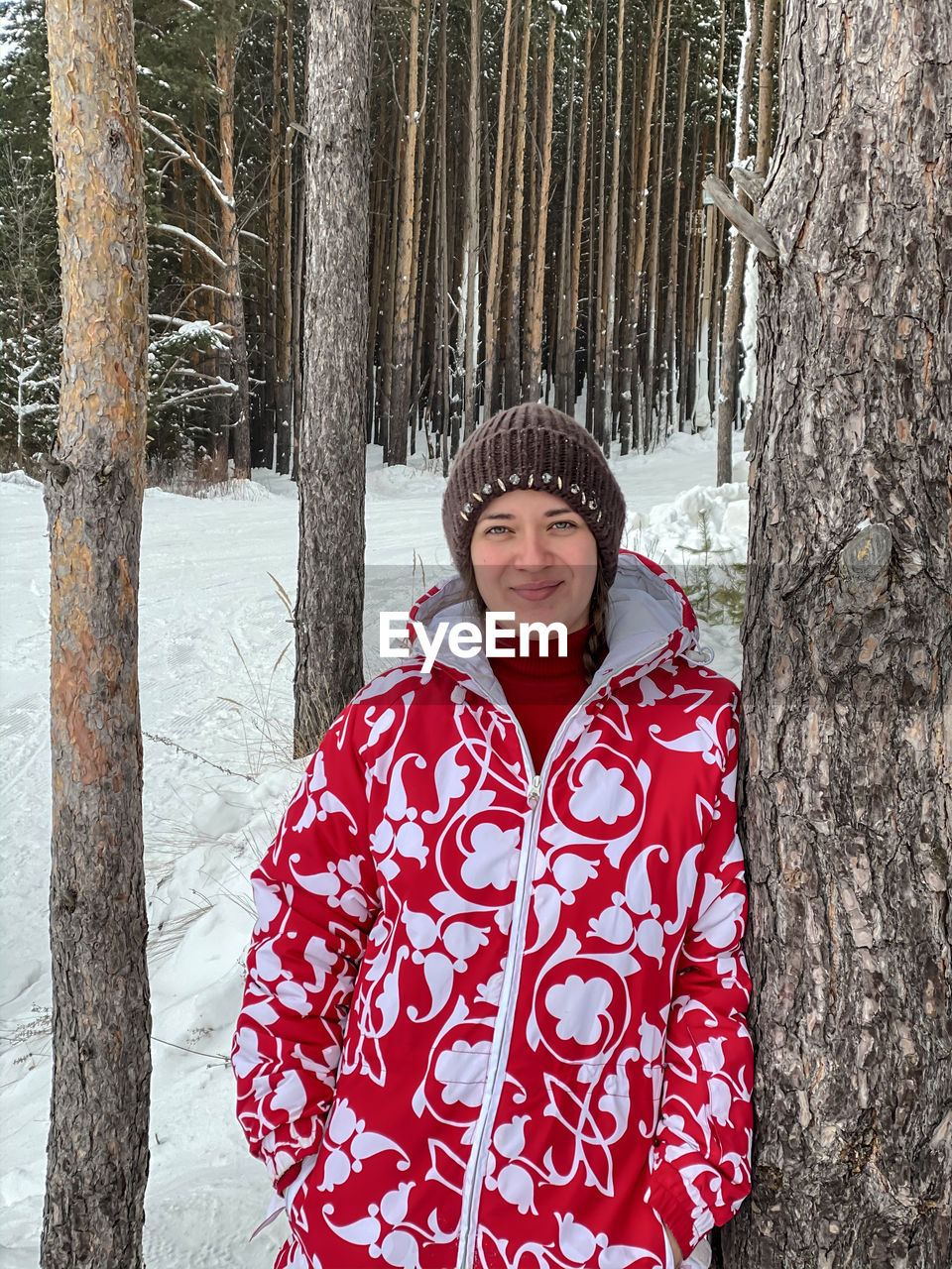 portrait of smiling young woman standing against trees