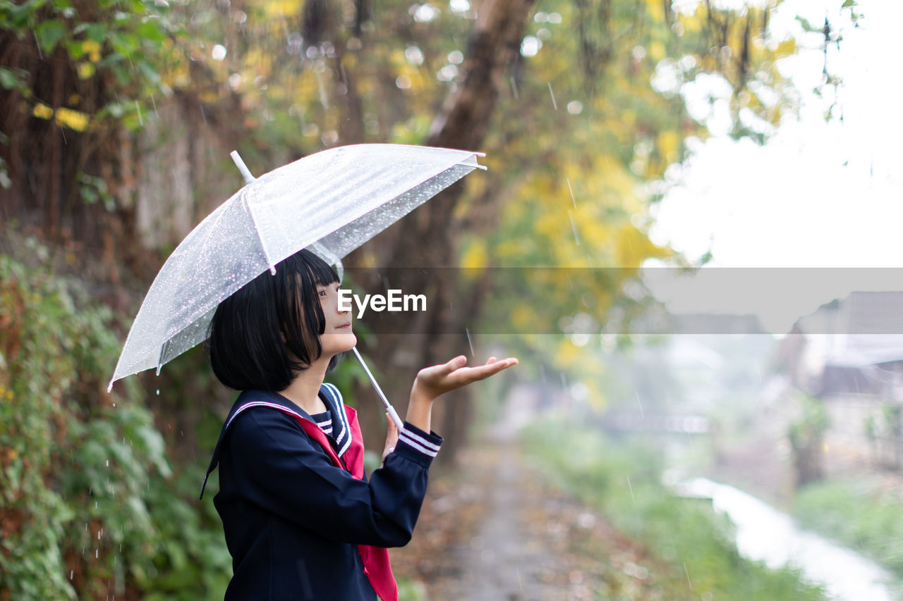 Woman with umbrella standing on rainy day