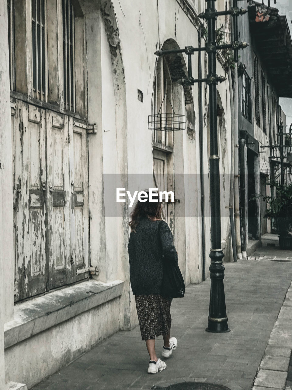 Rear view of woman walking on street amidst buildings