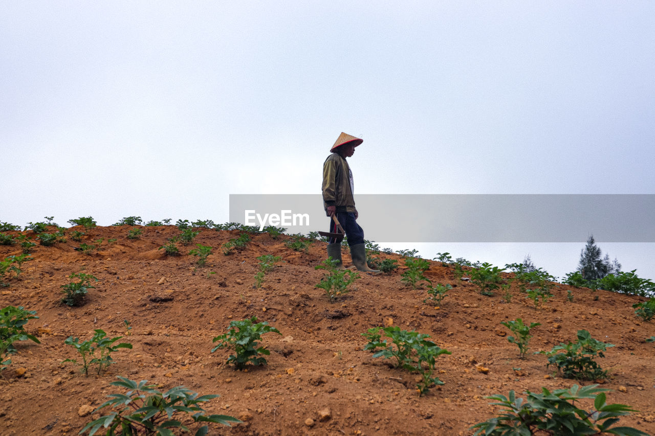 MAN STANDING ON FIELD AGAINST CLEAR SKY