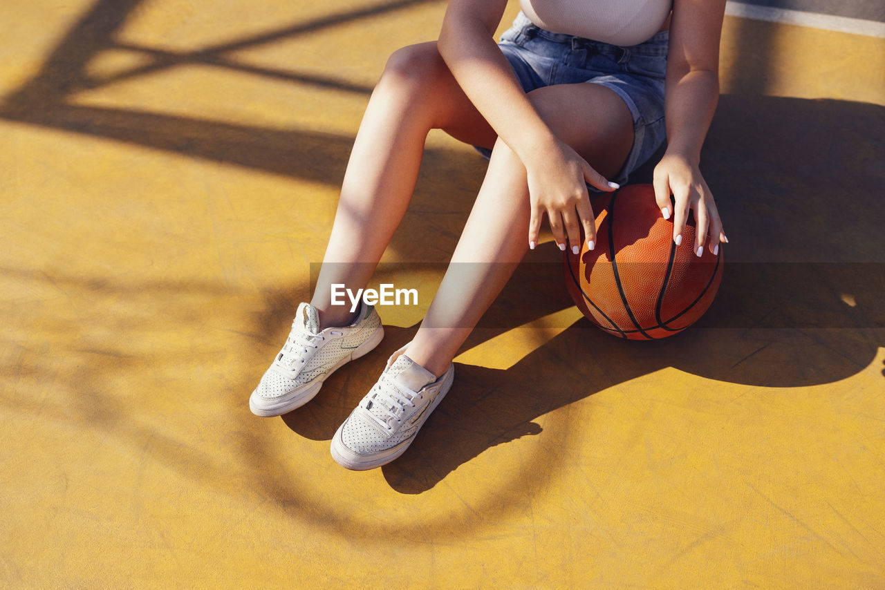 low section of woman playing basketball on floor