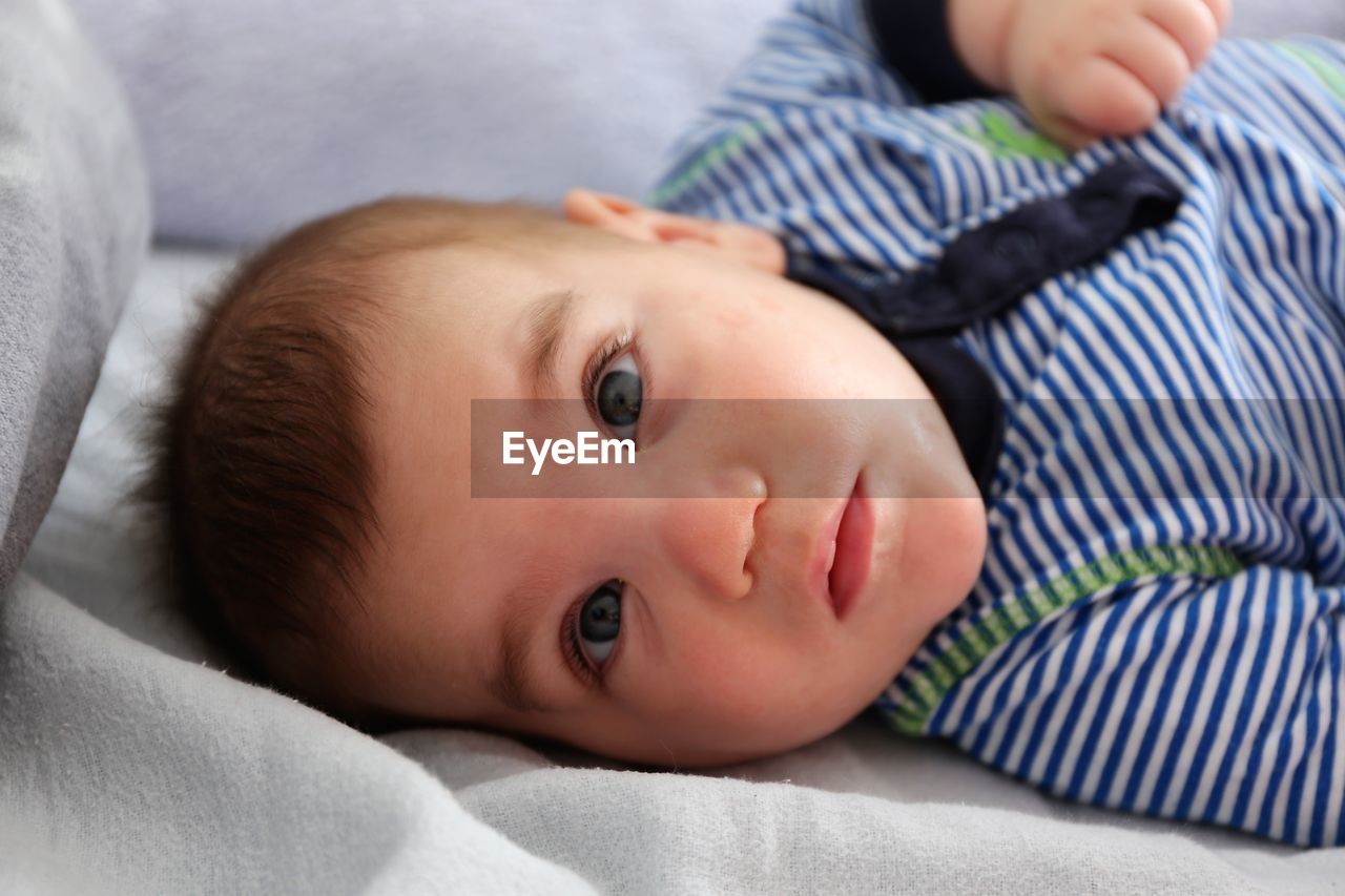 Portrait of cute baby boy lying on bed