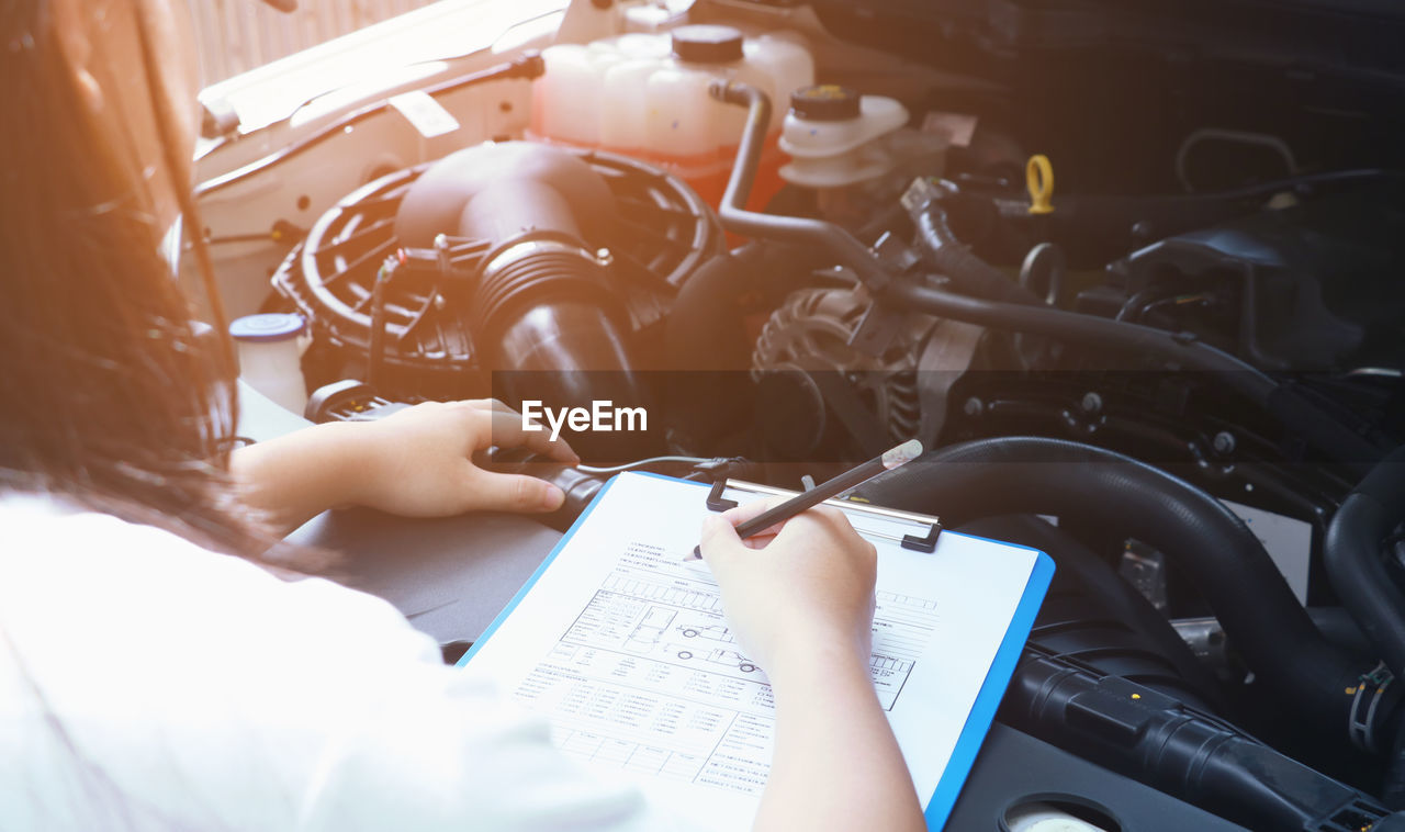 Woman examining car engine