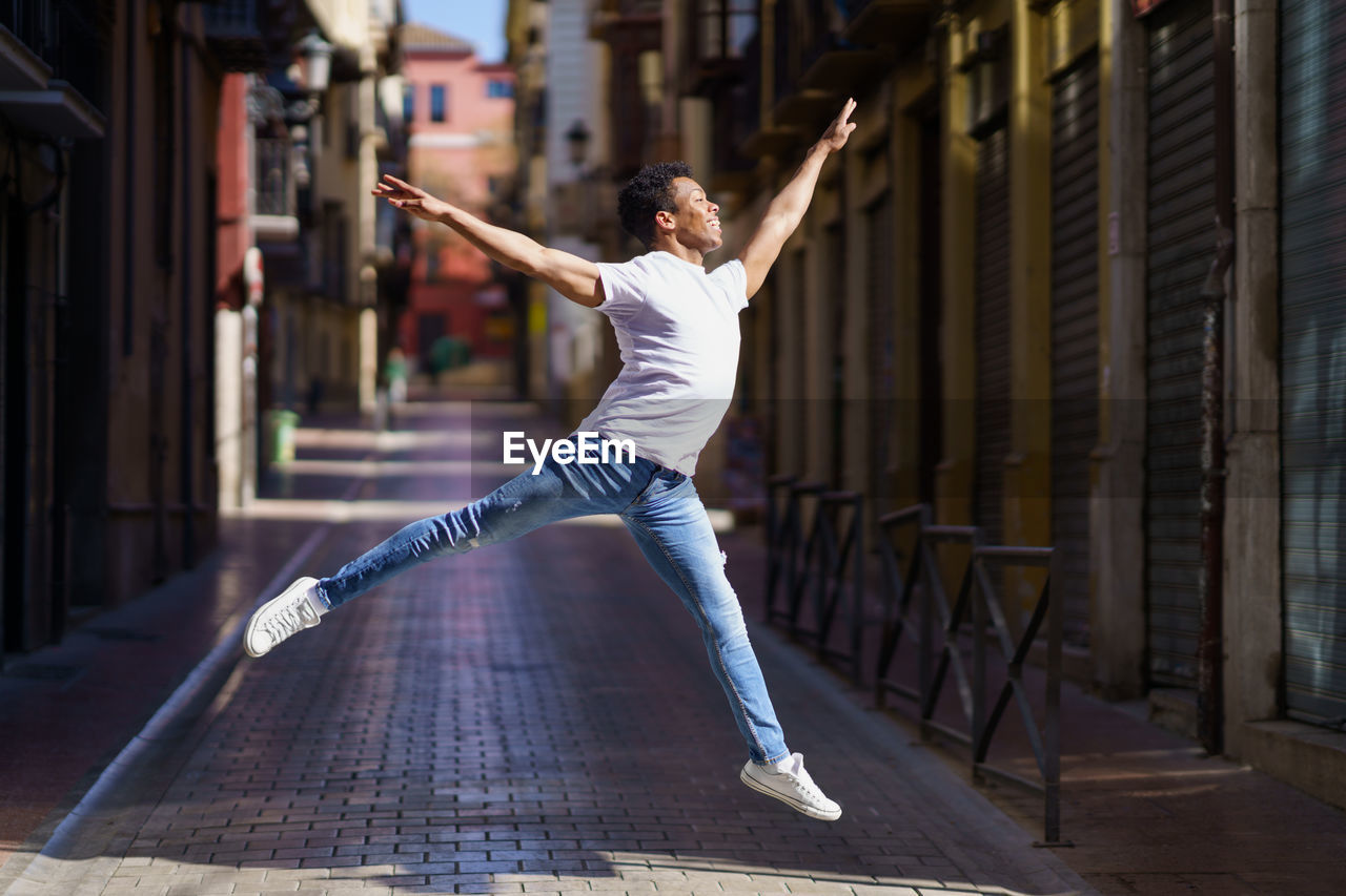 Full length of man jumping over street against building