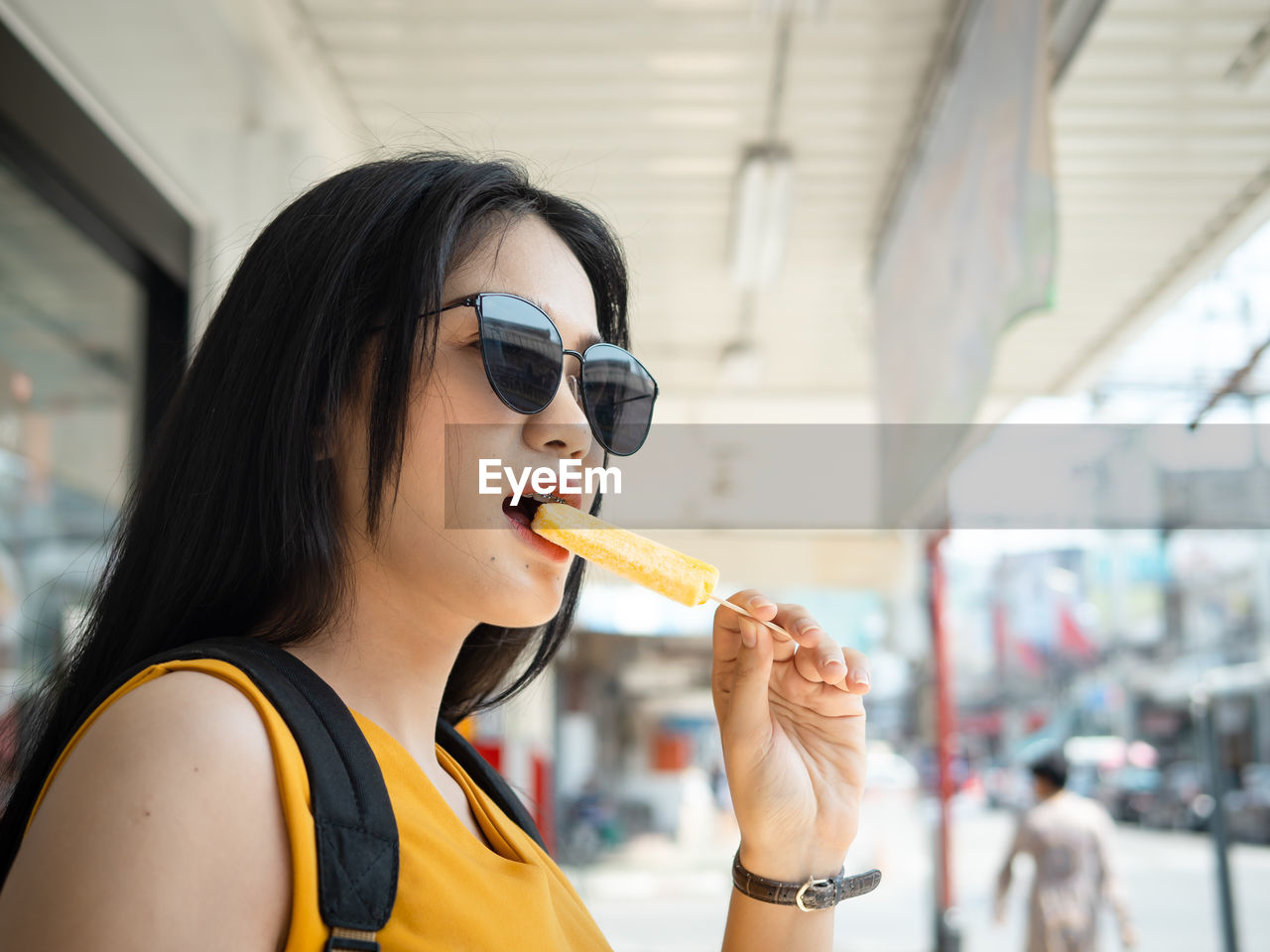 Young woman eating ice cream while standing outdoors
