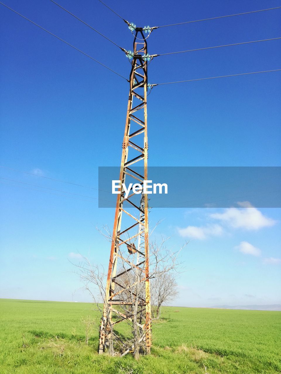 LOW ANGLE VIEW OF ELECTRICITY PYLON ON FIELD AGAINST SKY