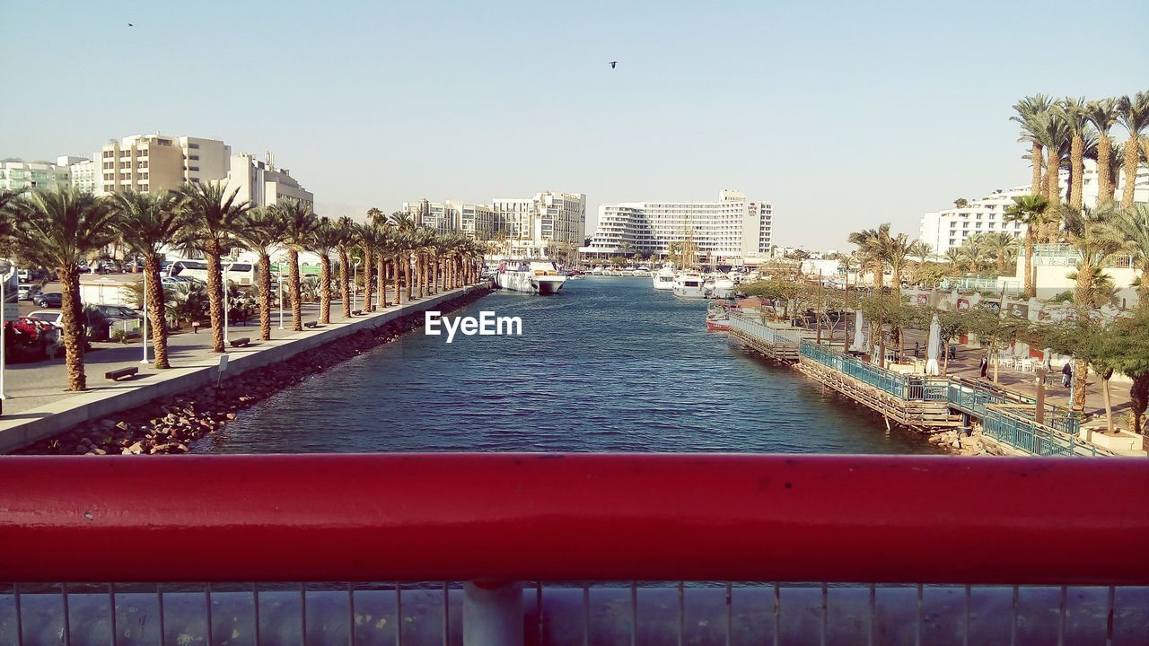 Canal in city against clear sky