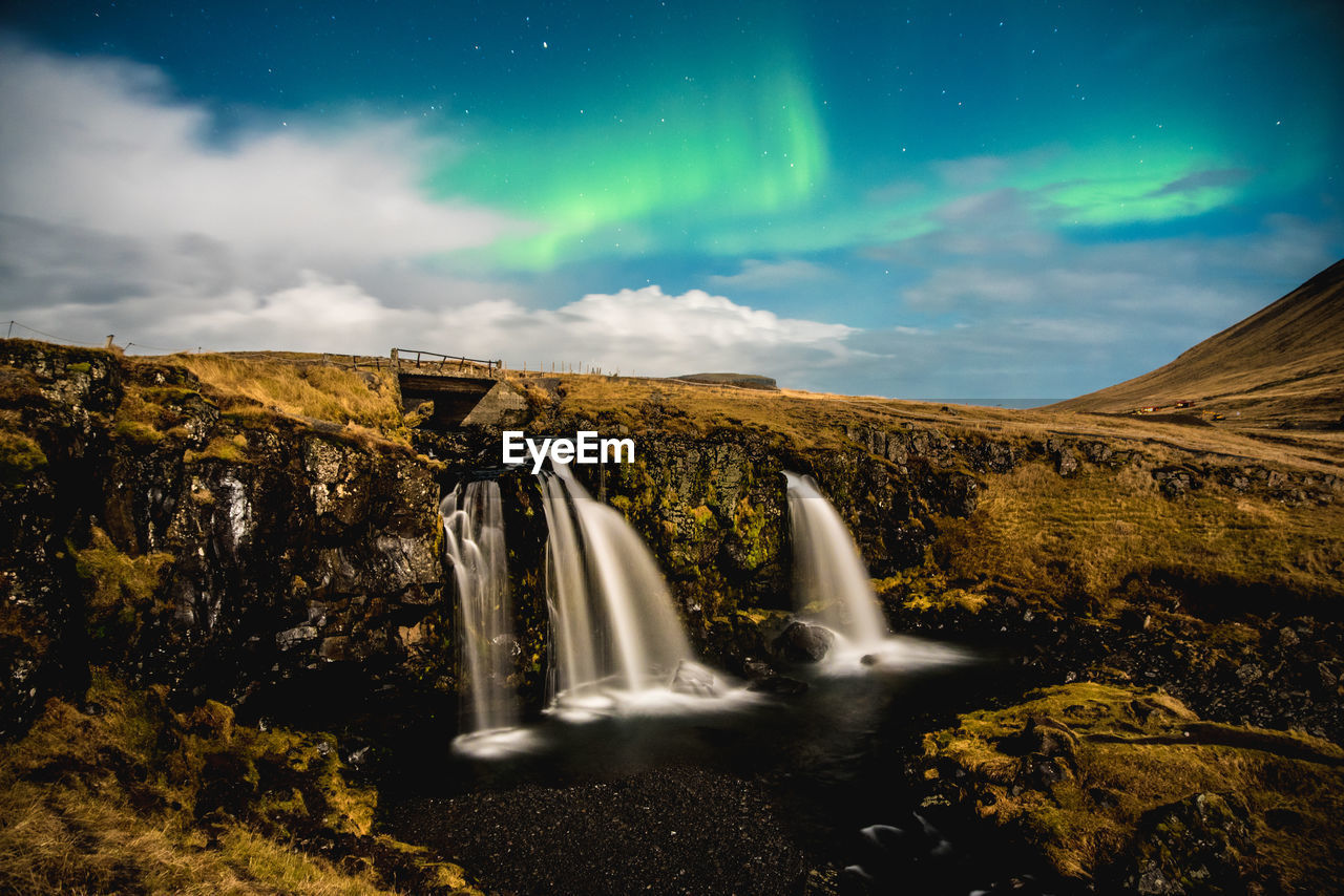 Scenic view of waterfall against night sky with aurora borealis