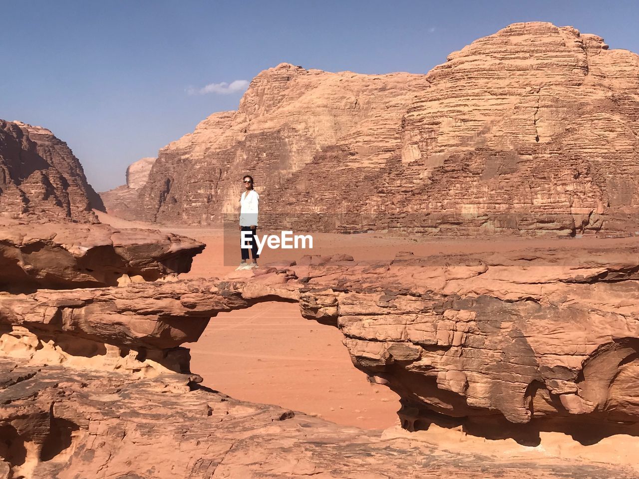 Woman standing on rock formation against sky