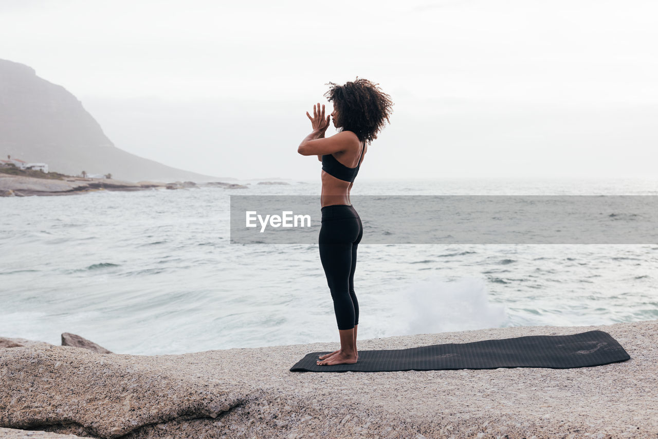 rear view of woman standing on beach against sky