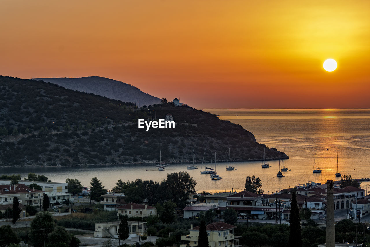 Ermioni town by sea against sky during sunset