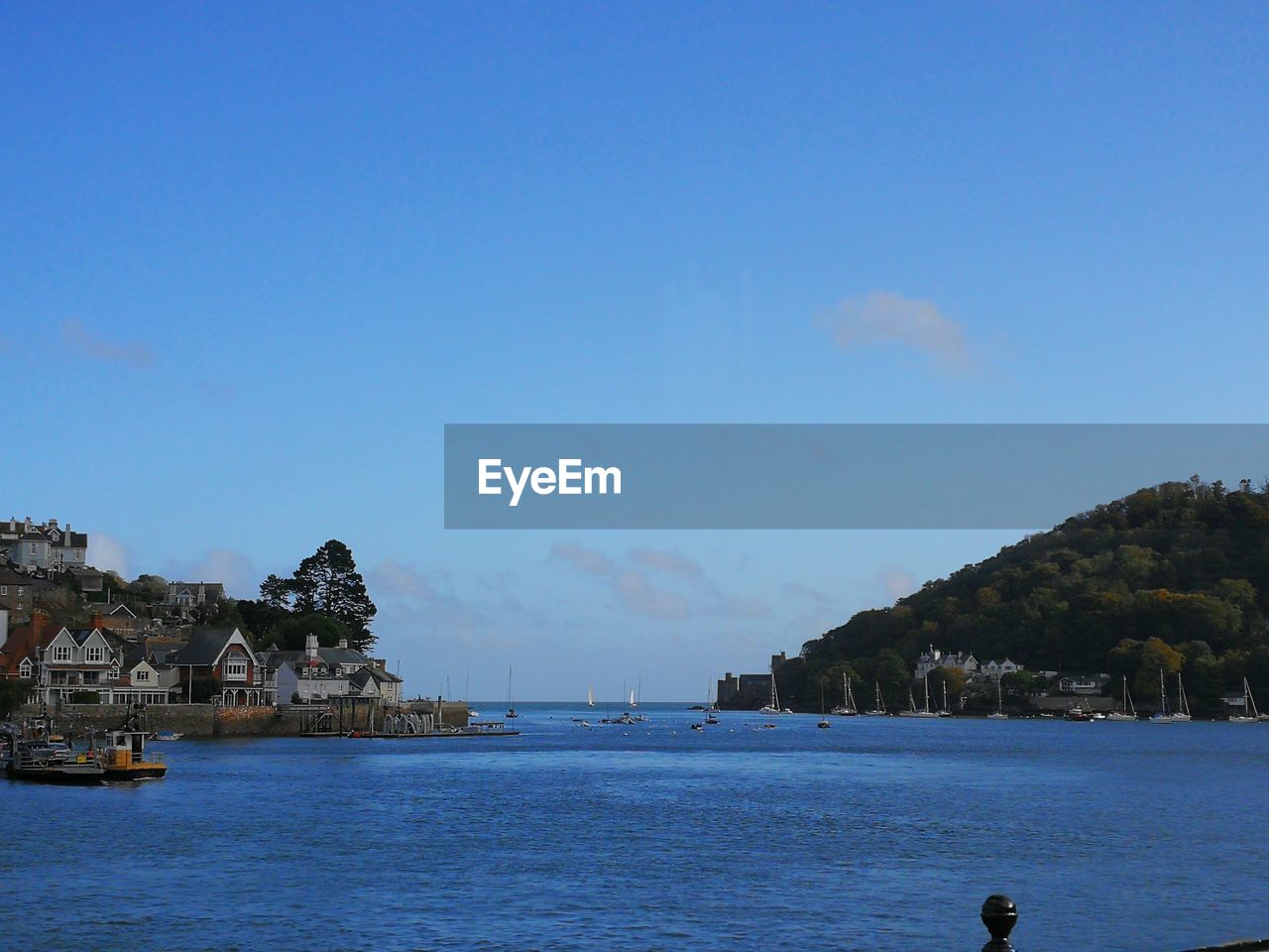 Scenic view of sea by town against clear blue sky