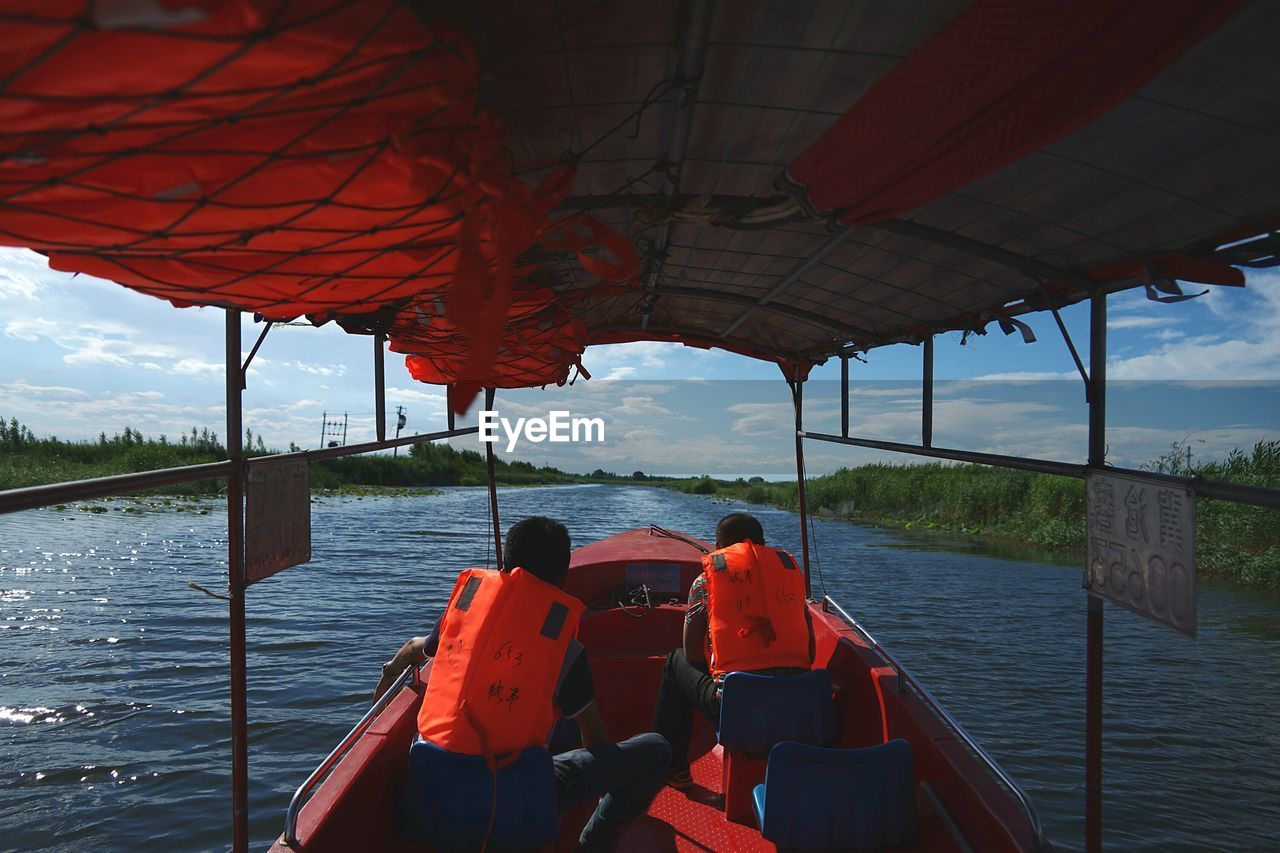 Rear view of boating in calm lake