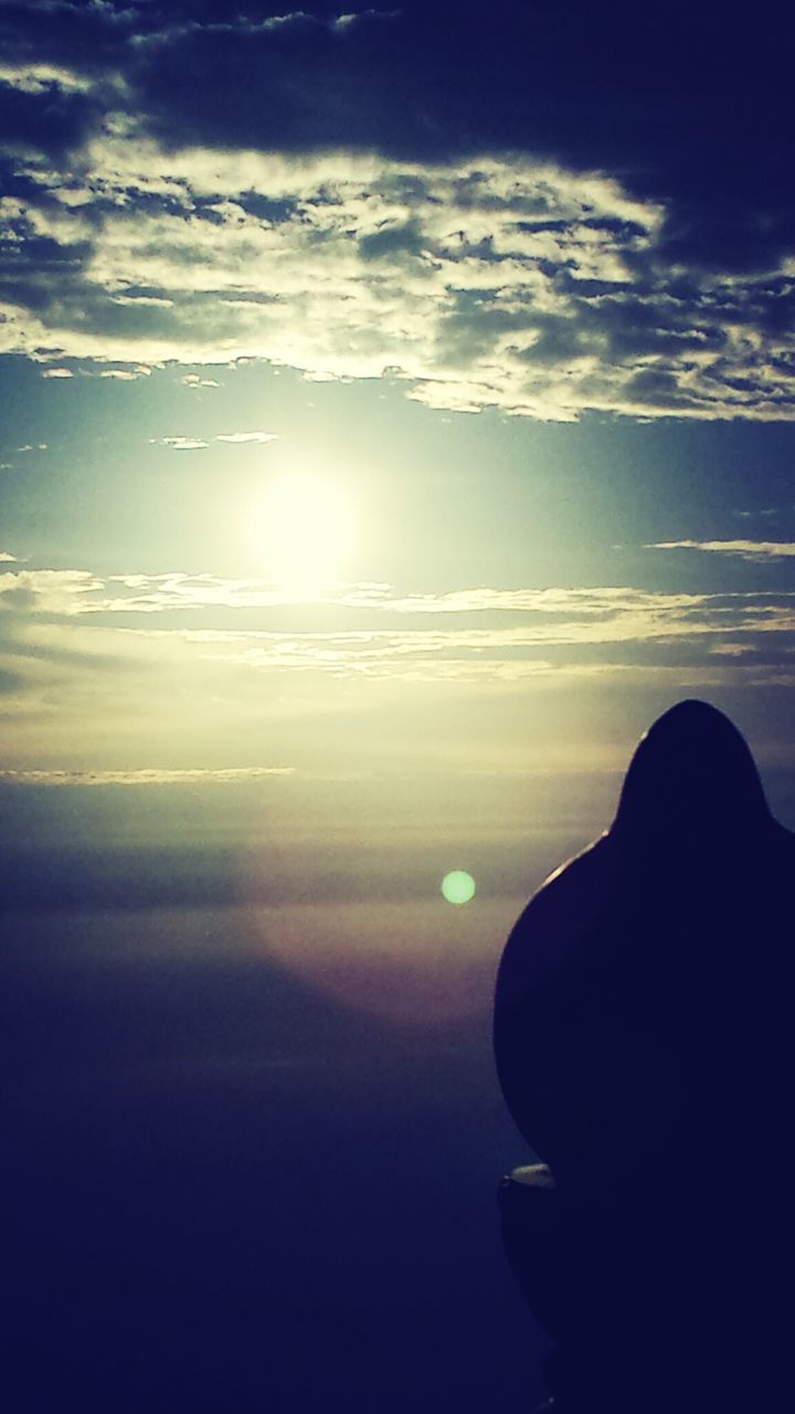 SUN SHINING THROUGH CLOUDS OVER LANDSCAPE