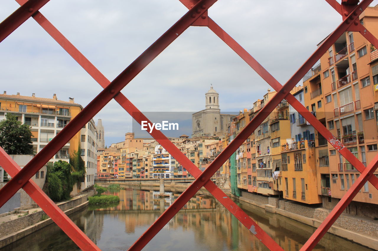 Buildings and canal in city seen through fence