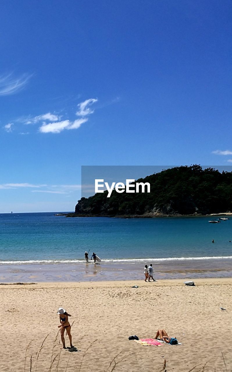 PEOPLE ON BEACH AGAINST BLUE SKY