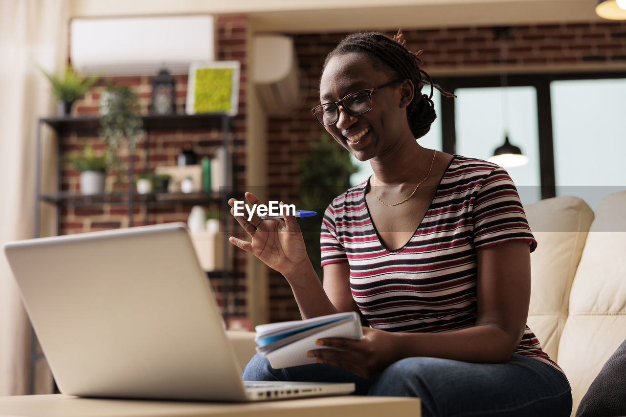 young woman using laptop while sitting on table