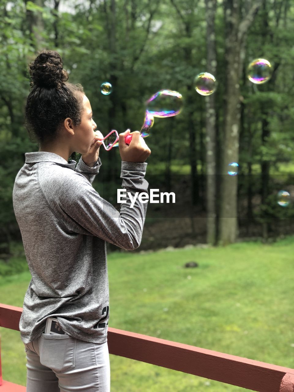 Full length of young woman in park having fun with bubbles 