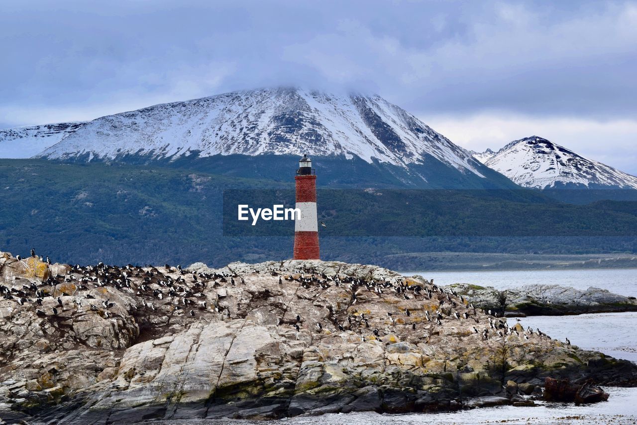 Lighthouse on snowcapped mountain against sky