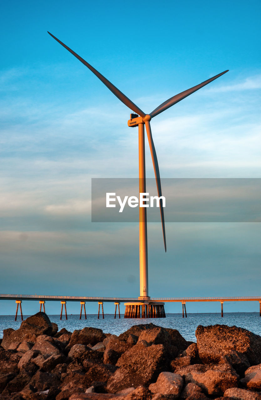 low angle view of wind turbines on beach against sky