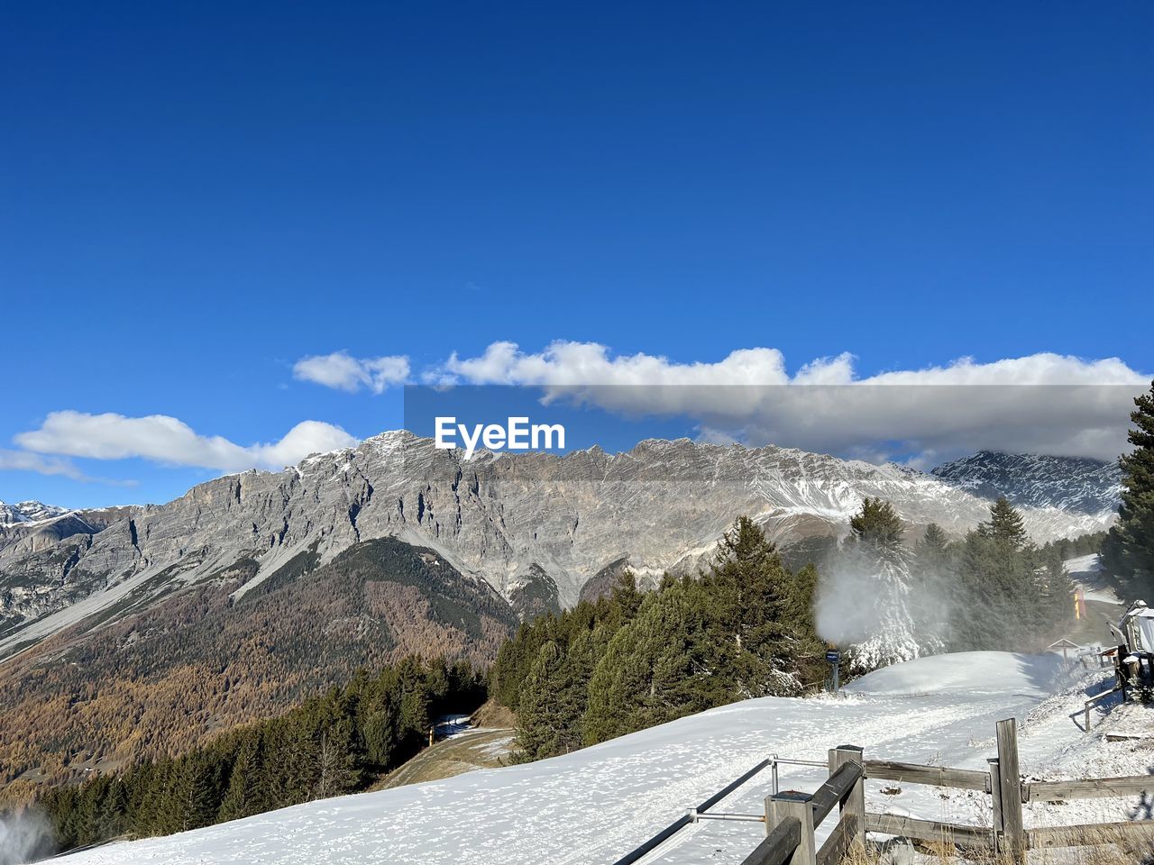 View over snowcapped mountain and snow cannons running in bormio, italy