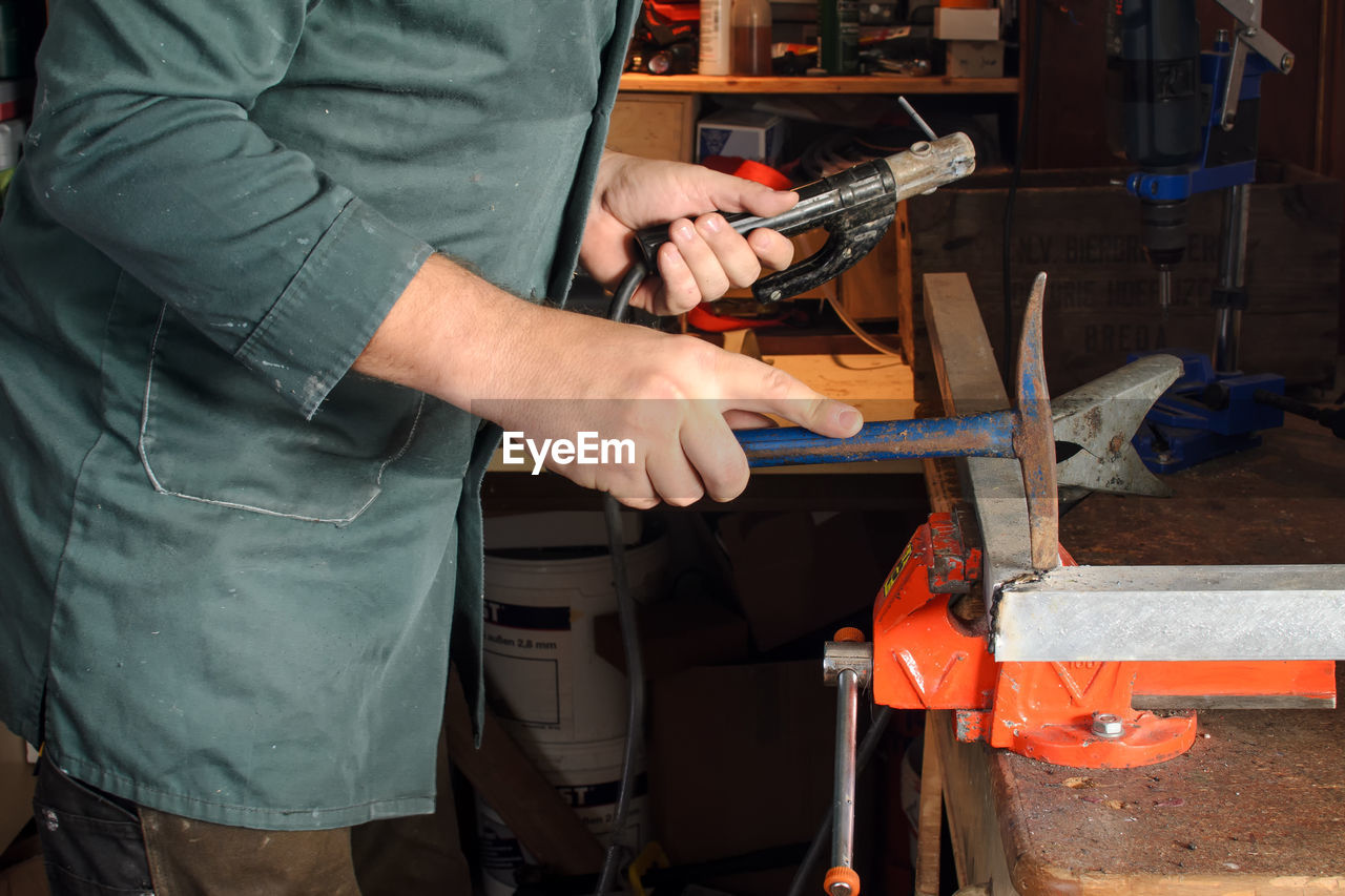 Midsection of man working on metal at workshop