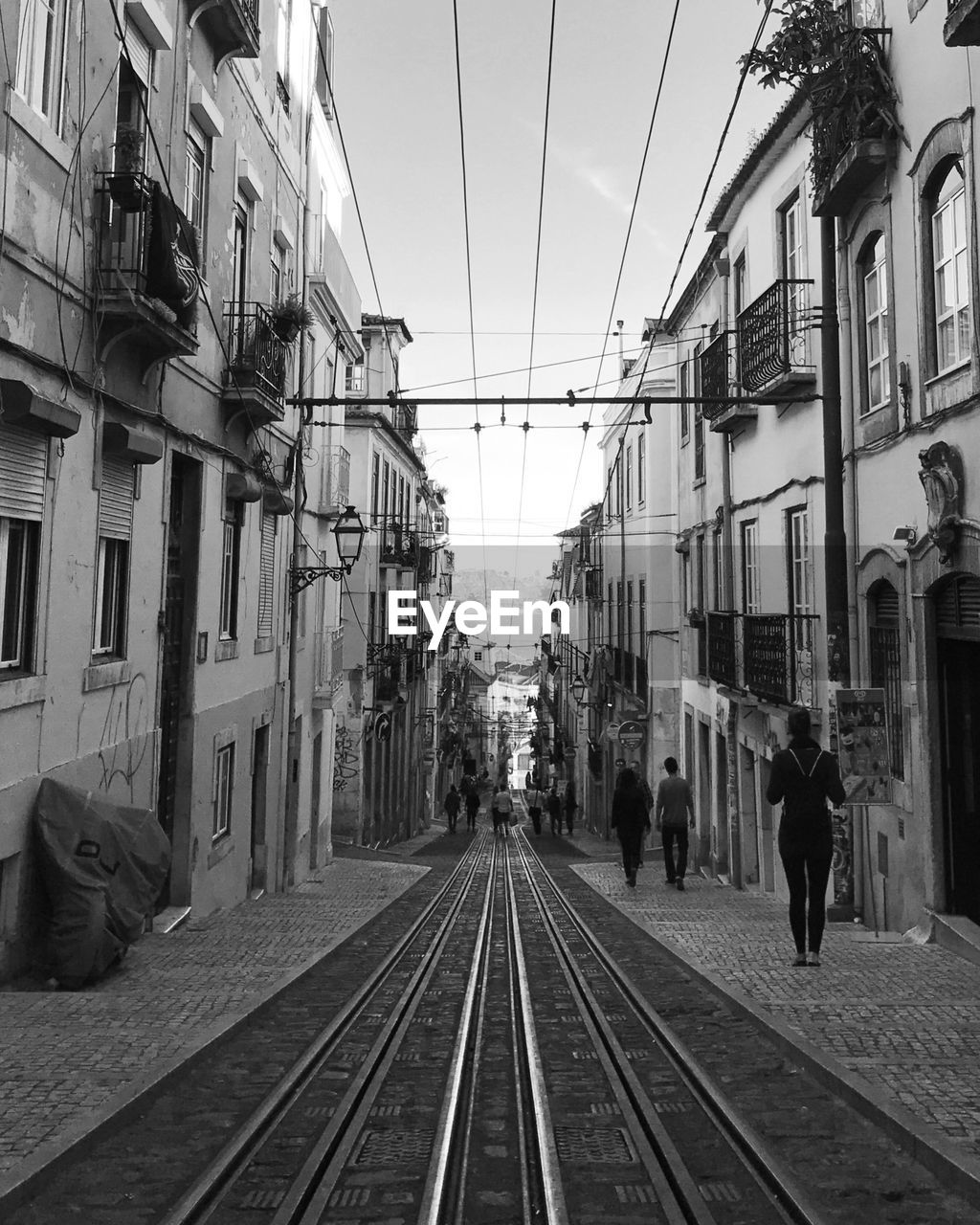 People on railroad tracks in lisbon against clear sky