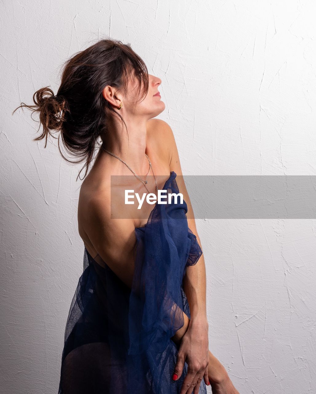 Portrait of young woman standing against wall