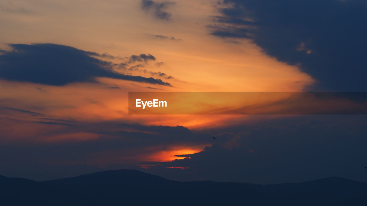 LOW ANGLE VIEW OF DRAMATIC SKY OVER SILHOUETTE MOUNTAINS