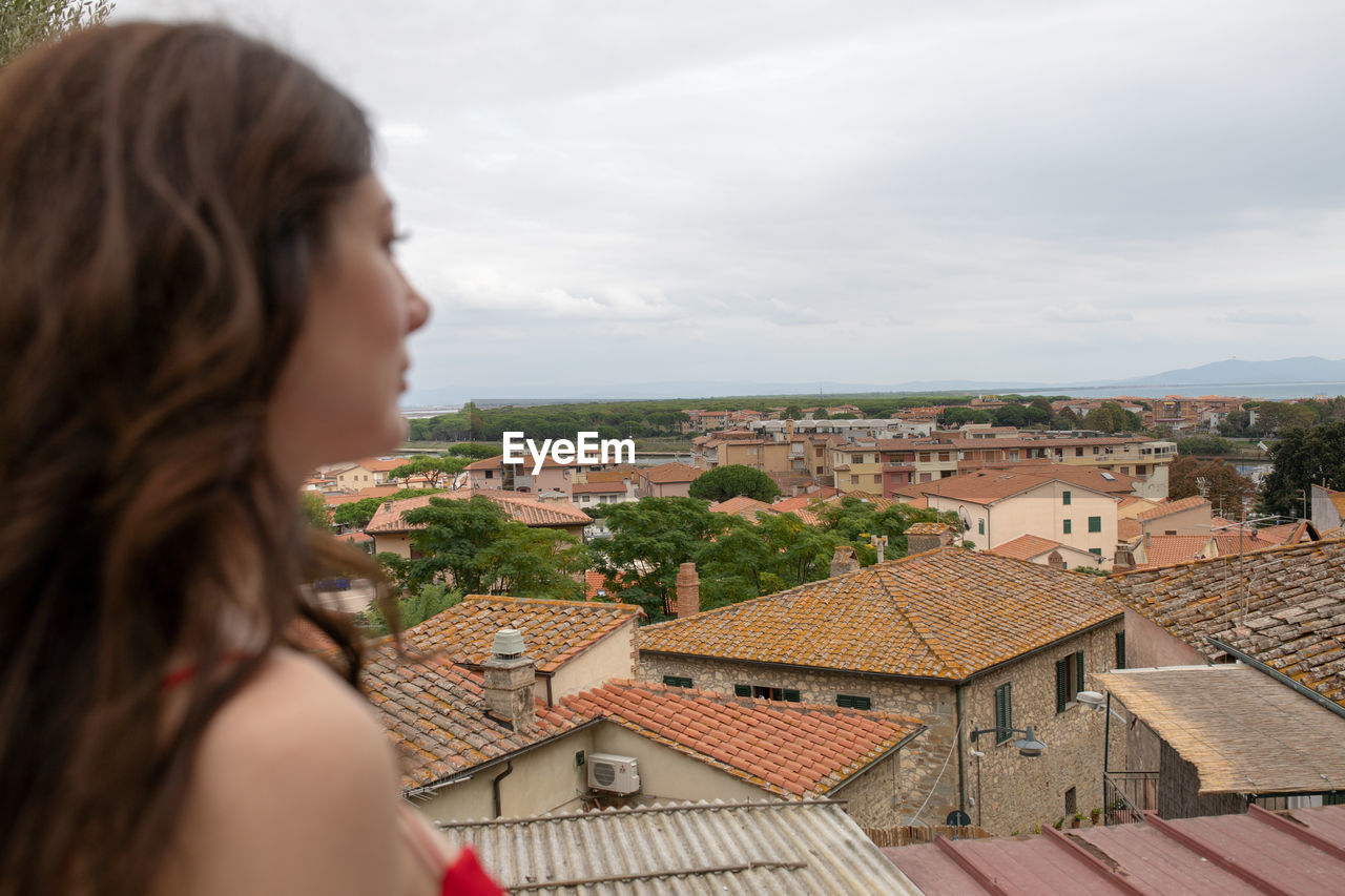 Beautiful woman looking away in city against sky