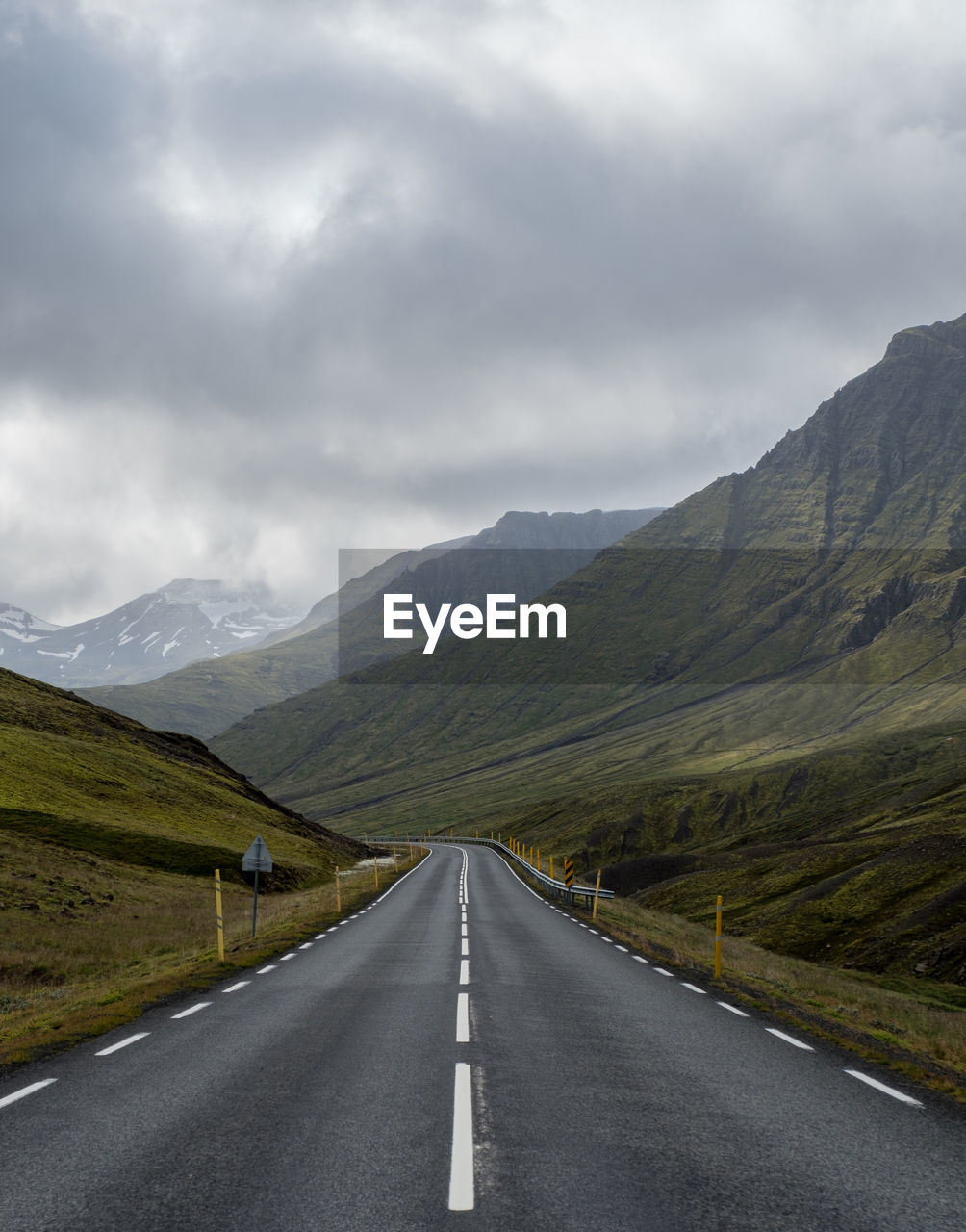 Empty road leading towards mountains against sky