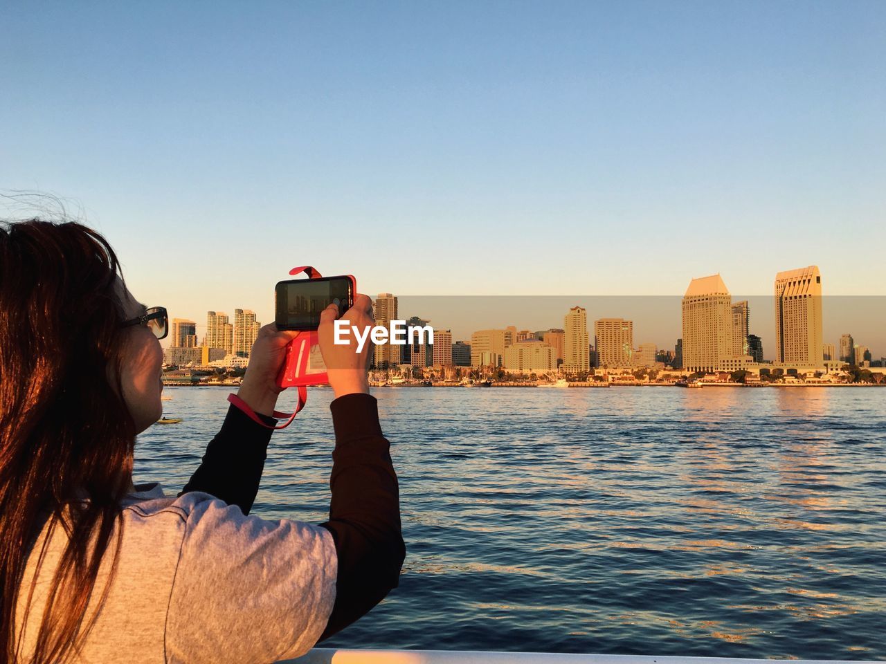 MAN PHOTOGRAPHING BY CITYSCAPE AT SUNSET