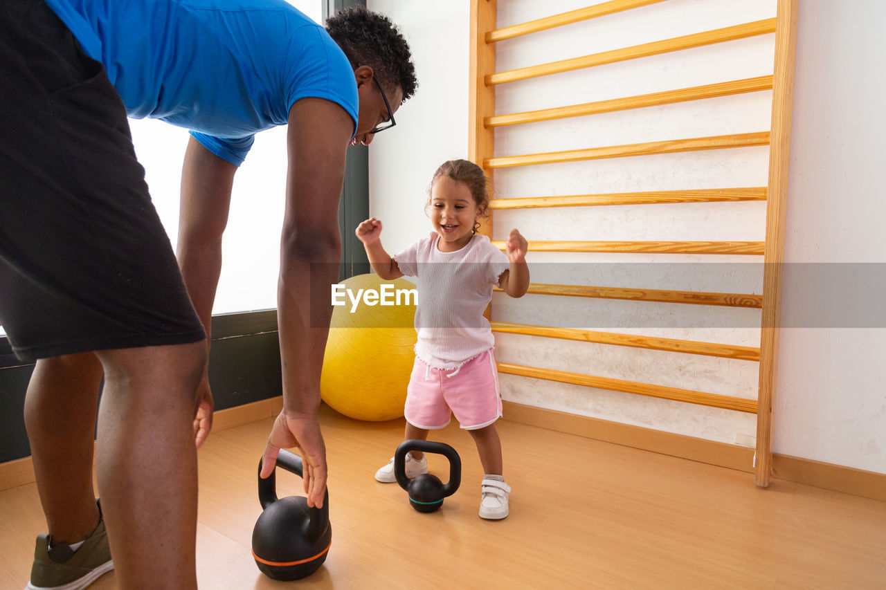 Little kid lifting kettlebell near father