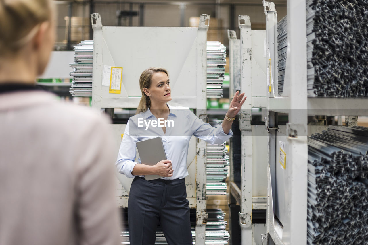 Woman with laptop in high rack warehouse