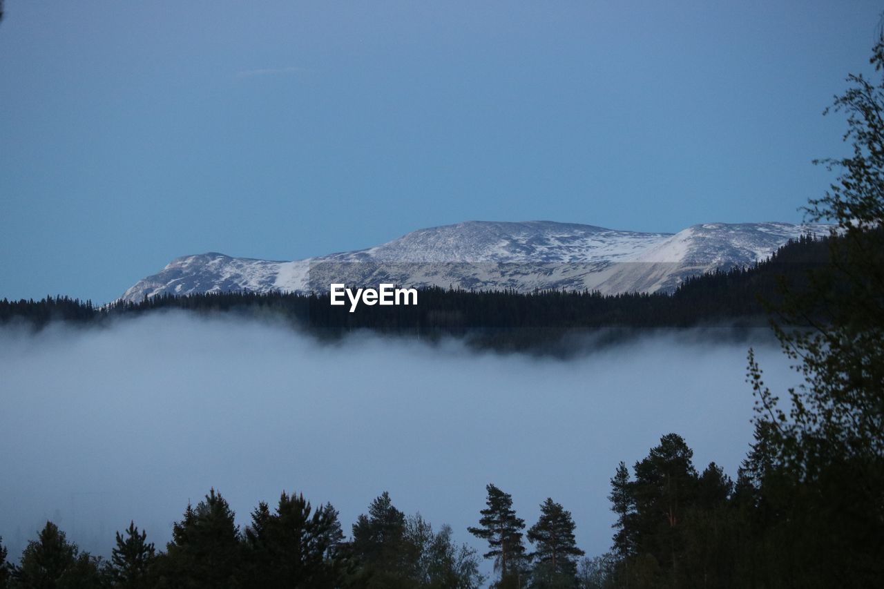 Low angle view of snowcapped mountains against clear blue sky