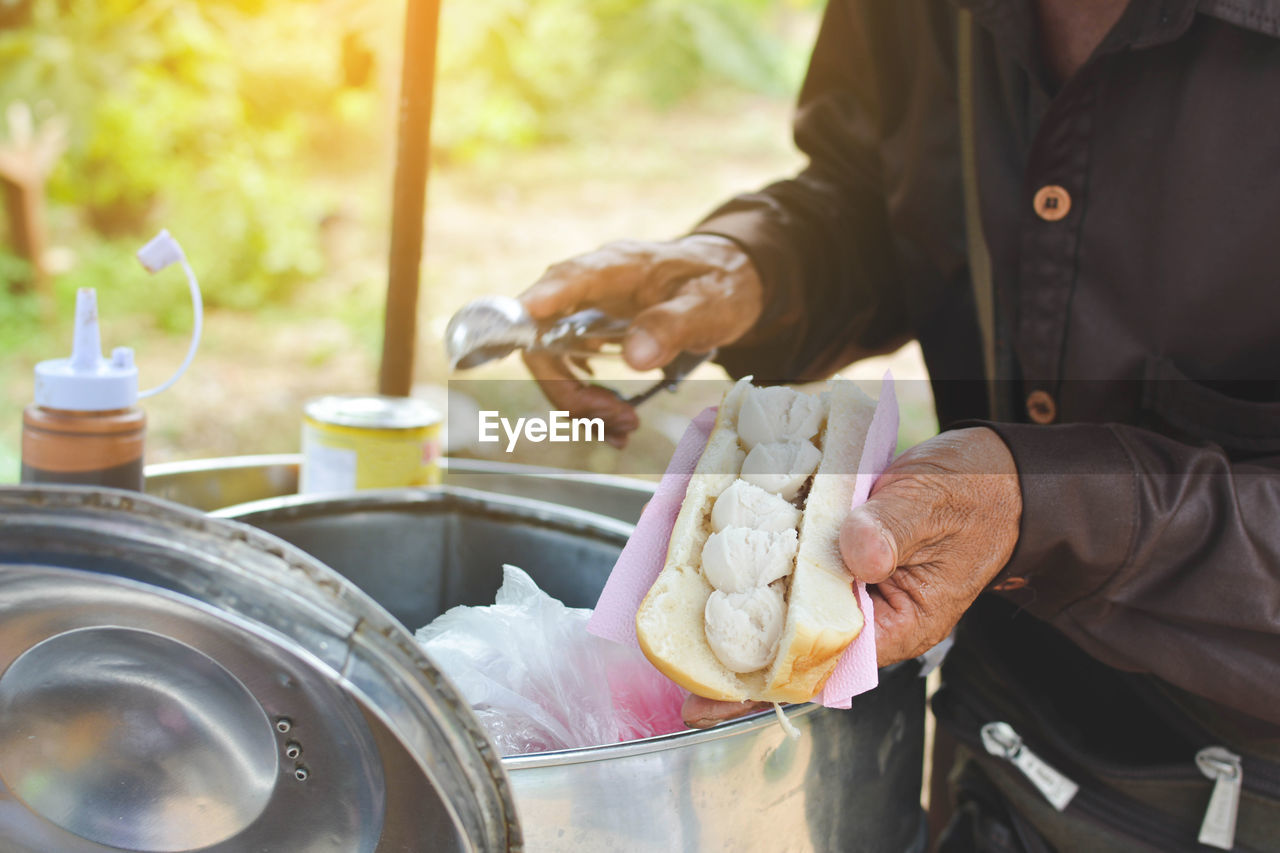 Midsection of vendor holding ice cream sandwich